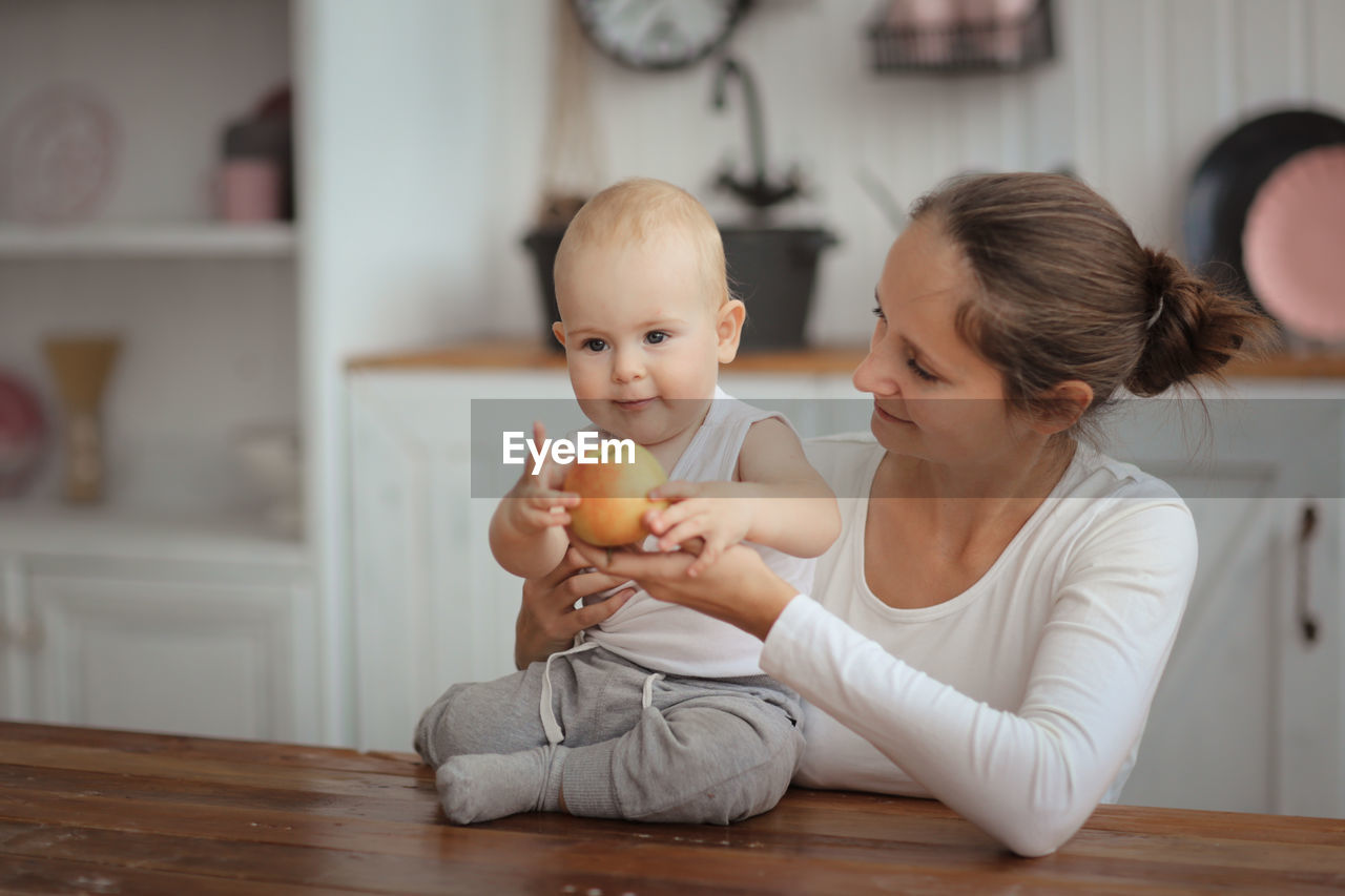 Baby with an apple an concept of a healthy childhood, mom's love