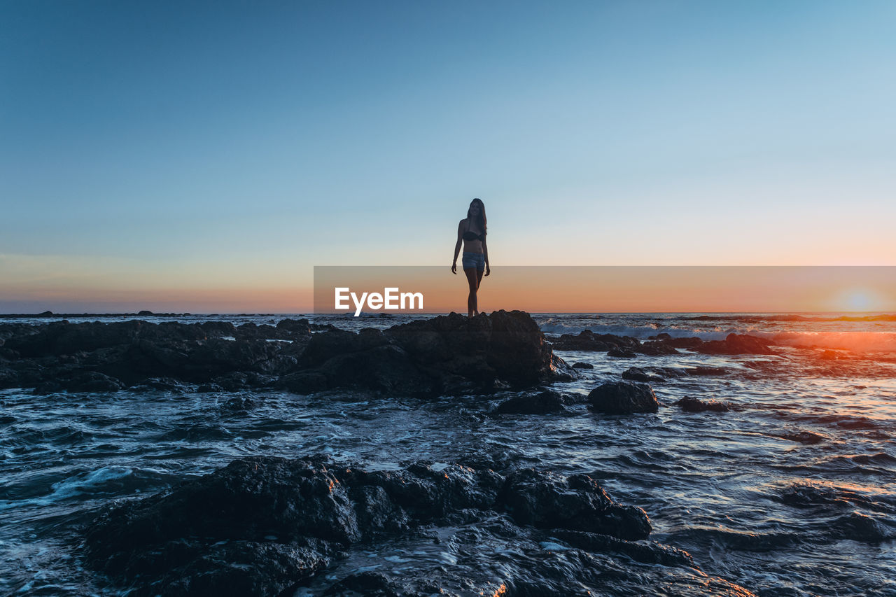 Woman standing at calm sea