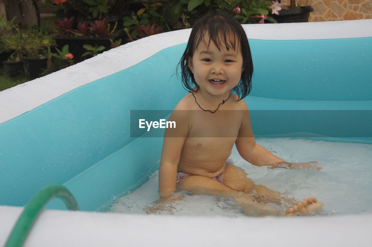 Portrait of girl sitting in inflatable pool