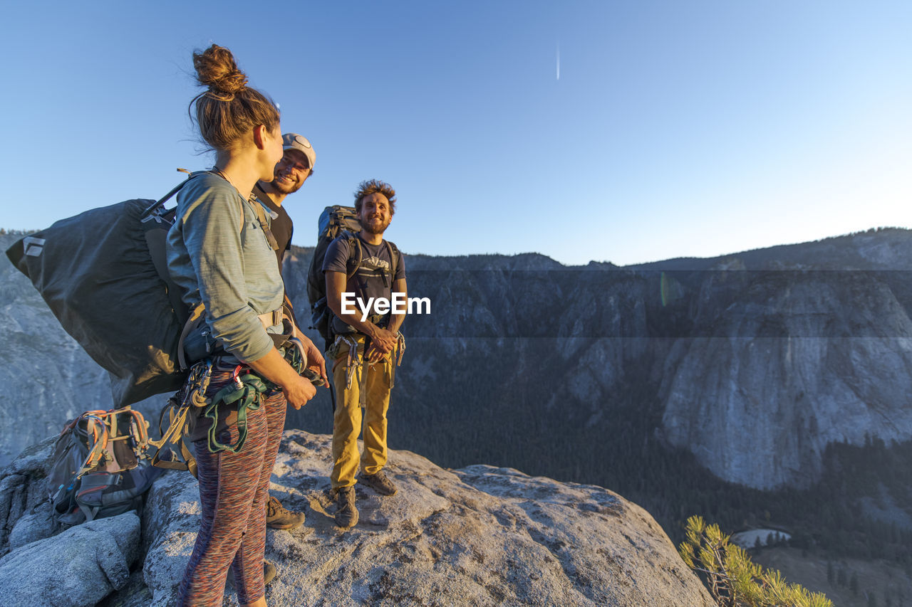 Three hikers at the top of el capitan in yosemite valley at sunset