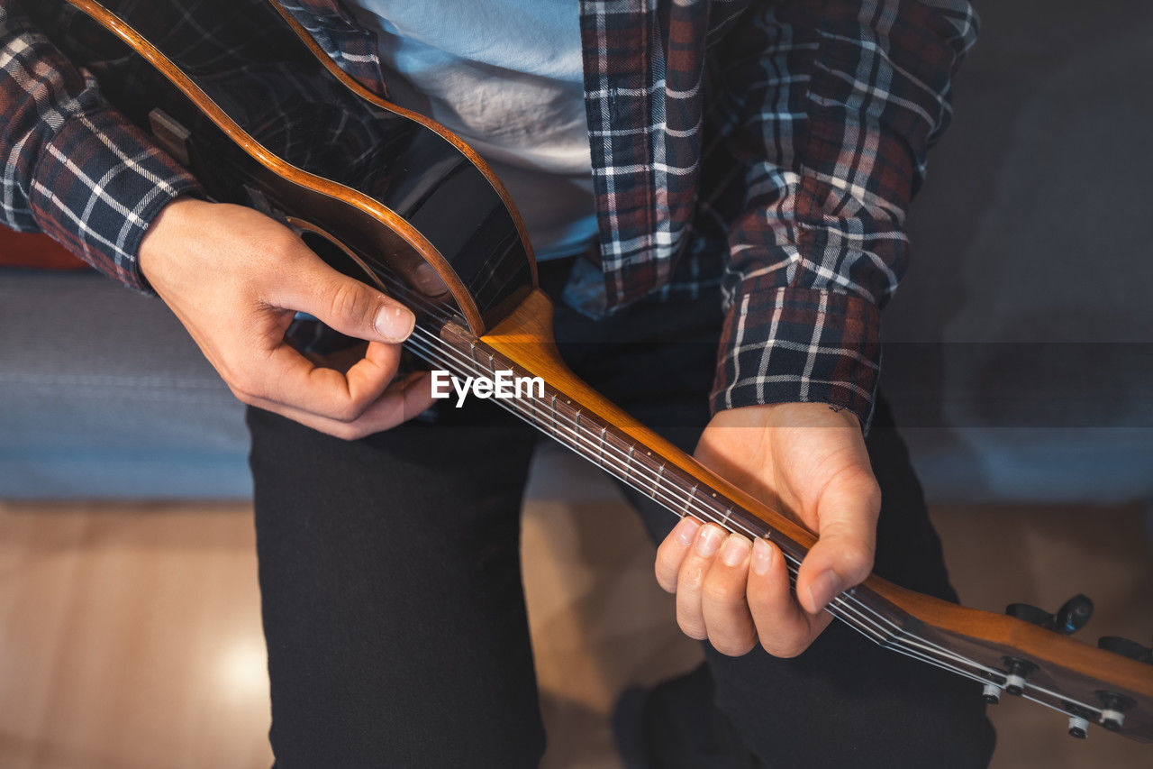 musical instrument, music, string instrument, musician, guitar, arts culture and entertainment, musical equipment, one person, adult, bass guitar, men, indoors, skill, midsection, performance, plucking an instrument, holding, hand, casual clothing, bowed string instrument, young adult, lifestyles, creativity, plucked string instruments, occupation, front view