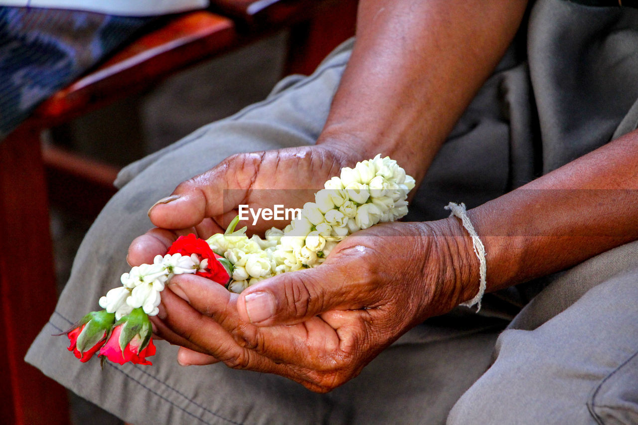 Midsection of woman holding flowers in hand