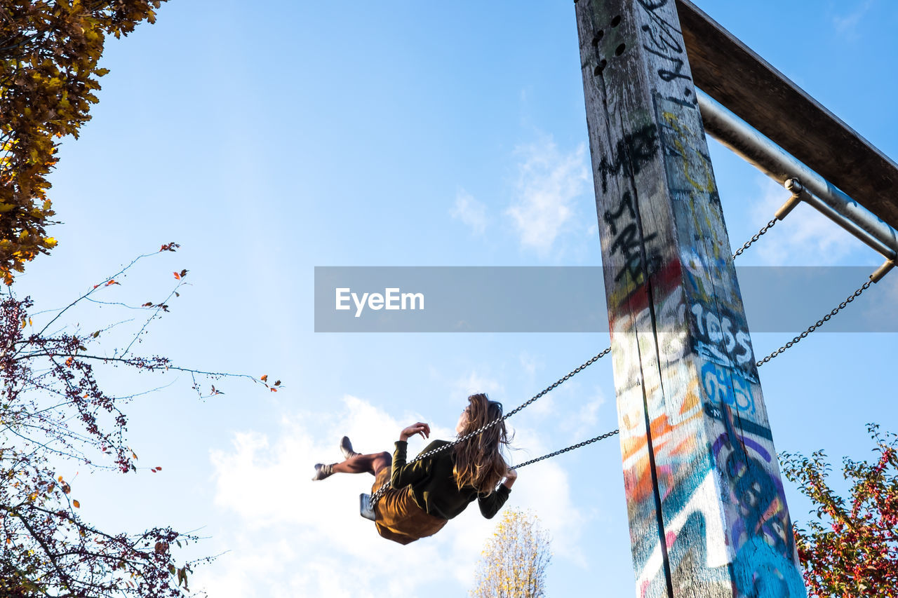 Low angle view of woman swinging against sky