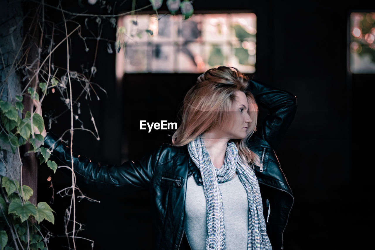 Young woman looking away while standing outdoors