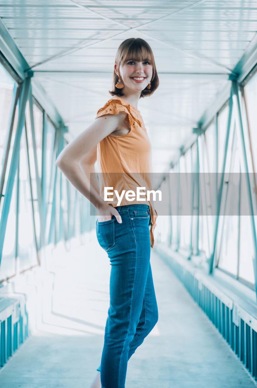 Portrait of smiling woman standing on footbridge