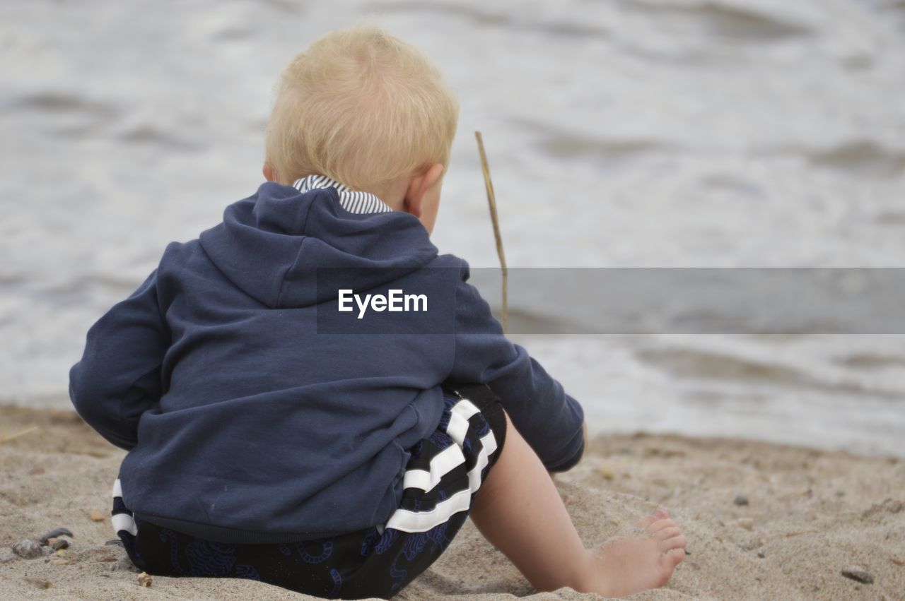 Rear view of boy sitting at beach