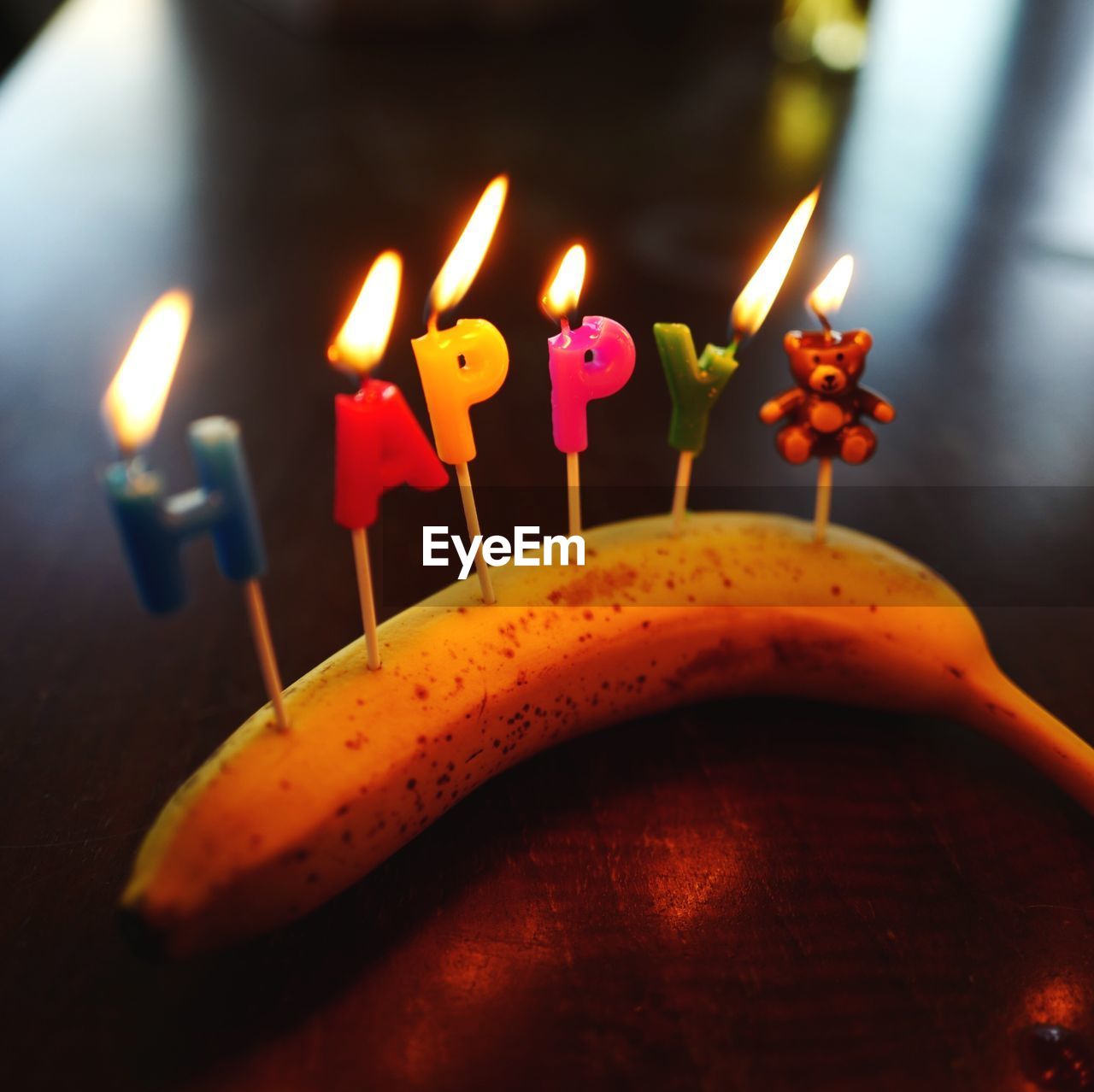 Close-up of birthday candles on banana at table