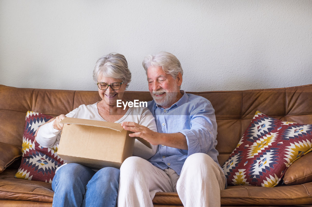 Smiling senior couple looking inside cardboard box