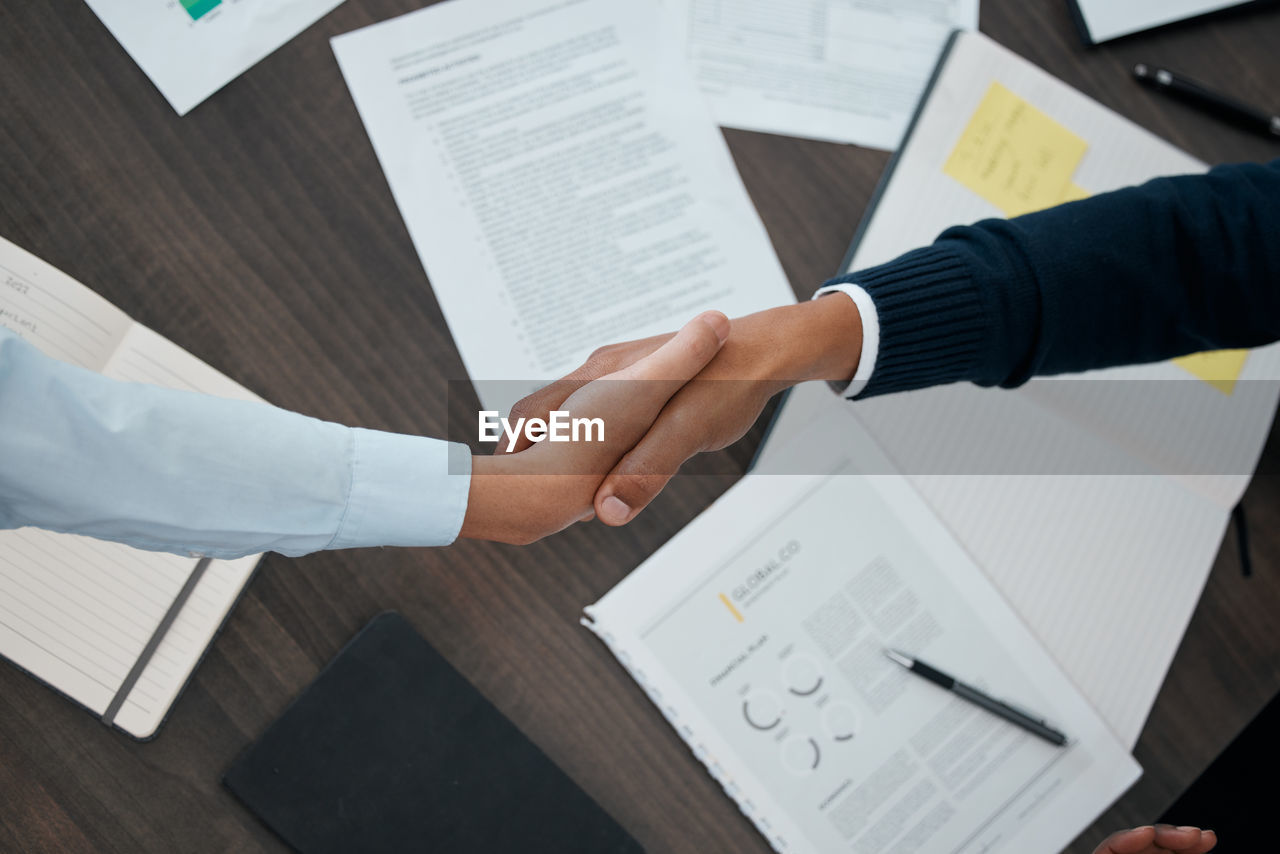 cropped image of business colleagues shaking hands on table