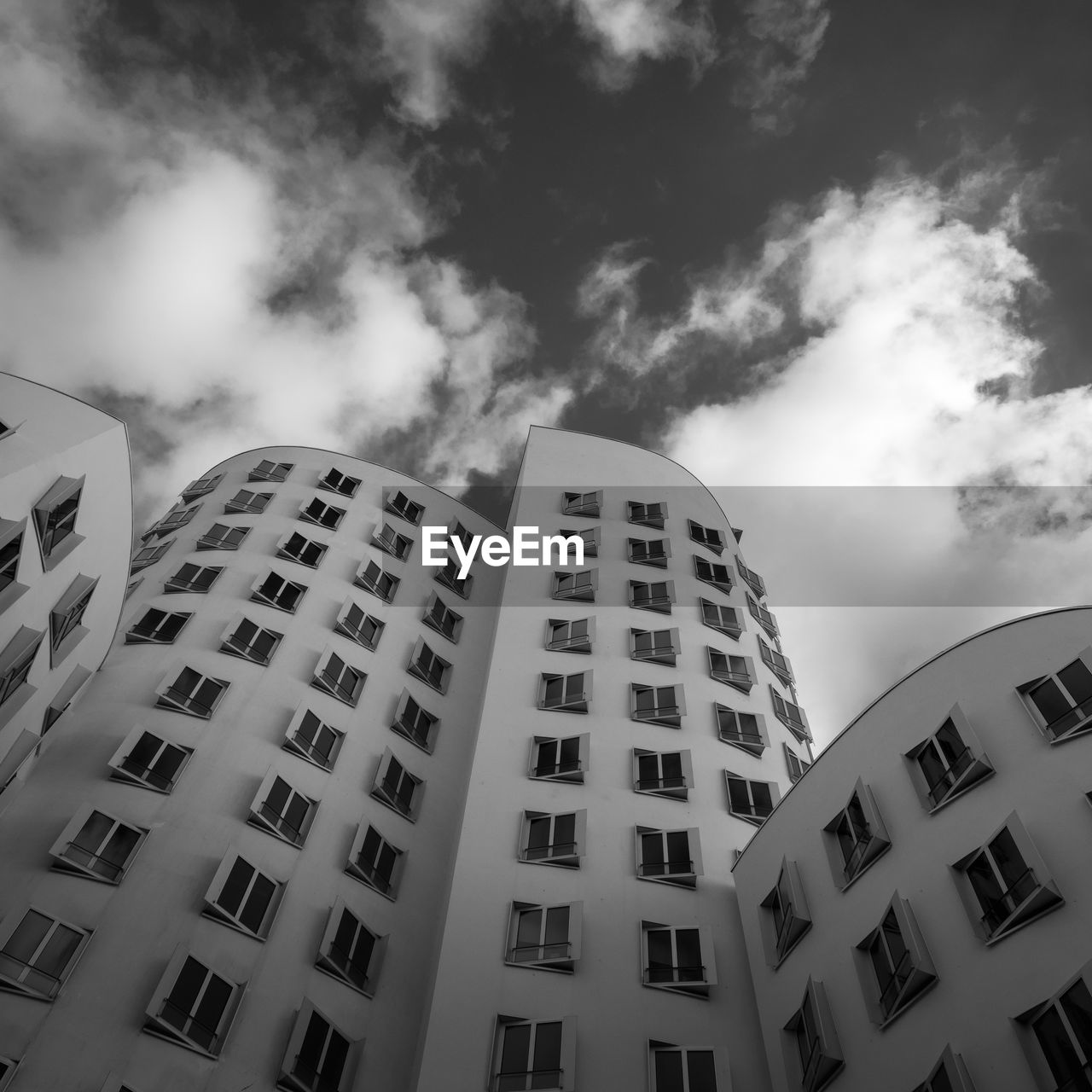 low angle view of modern buildings against cloudy sky