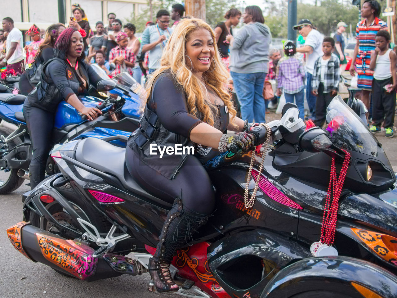 motorcycle, group of people, motorcycling, transportation, women, adult, vehicle, young adult, mode of transportation, happiness, crowd, enjoyment, smiling, sitting, race, leisure activity, day, large group of people, togetherness, emotion, lifestyles, men, land vehicle, friendship, sports, arts culture and entertainment, outdoors, female, full length, casual clothing, fun, racing, city, clothing, bonding, festival, teenager