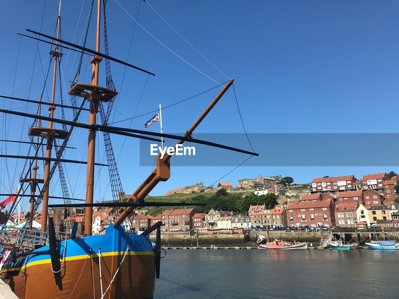 SAILBOATS MOORED AT HARBOR AGAINST CLEAR SKY