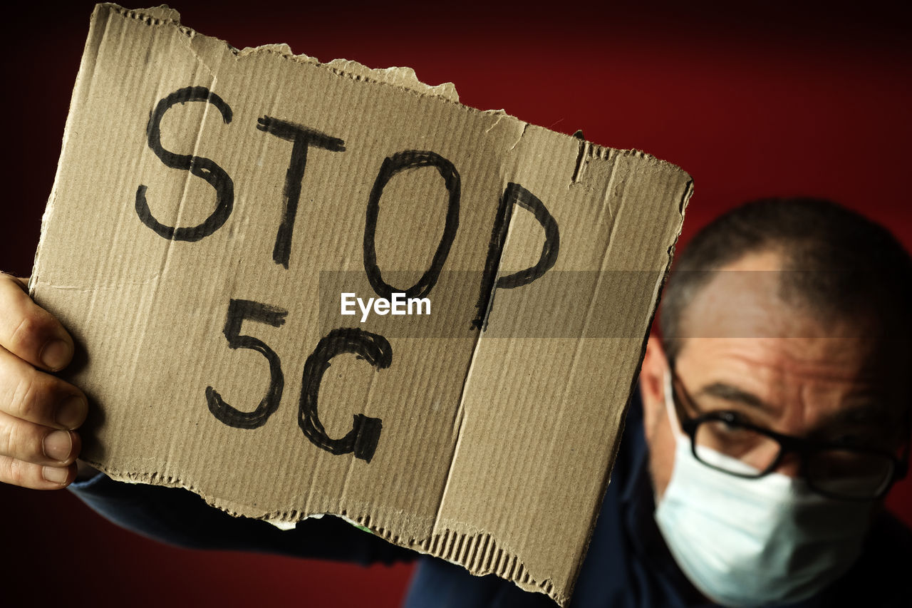 A man in a medical mask with a 5g stop poster. coronavirus fake news concept