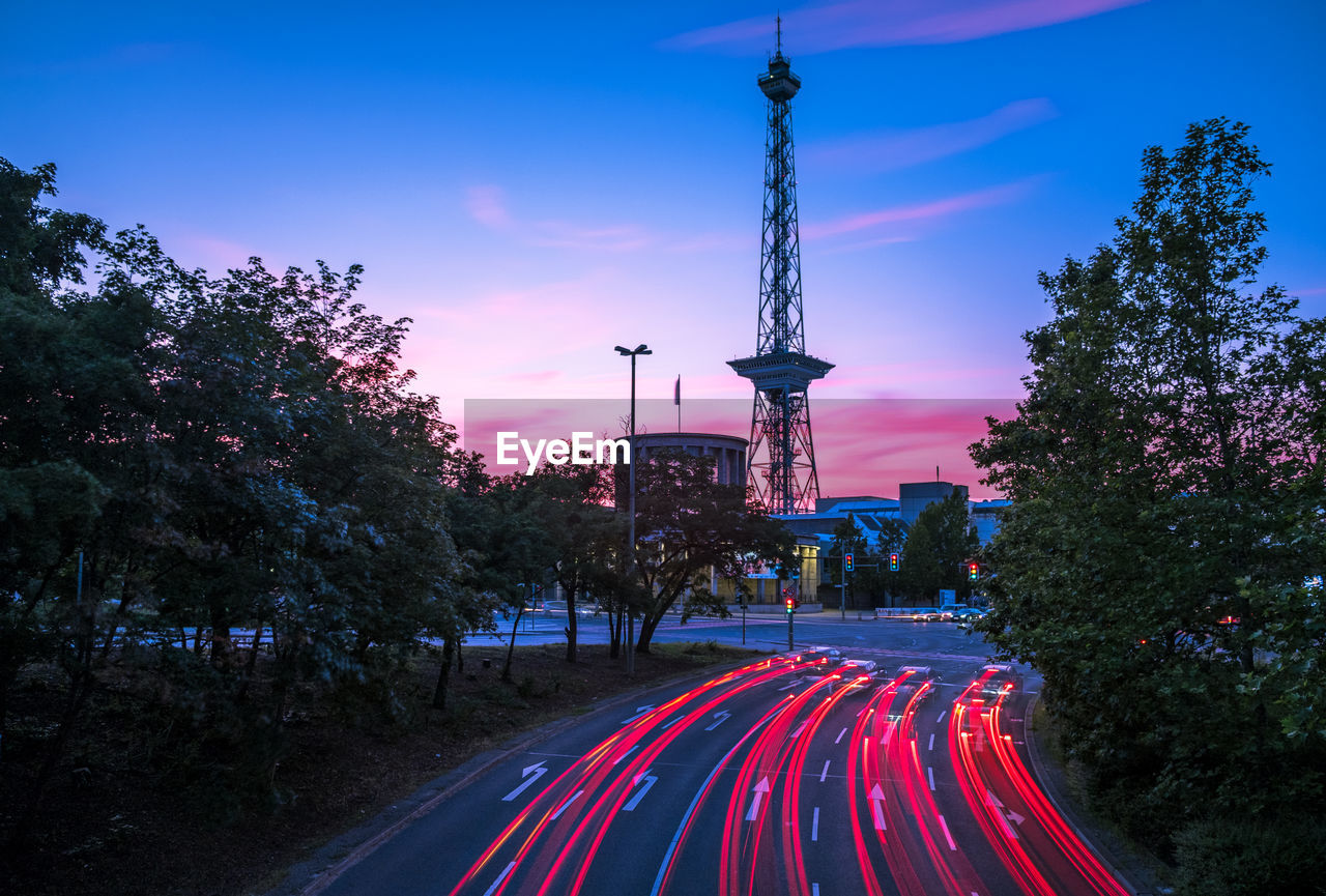 Light trails on road with berlin radio tower (funkturm) against sky