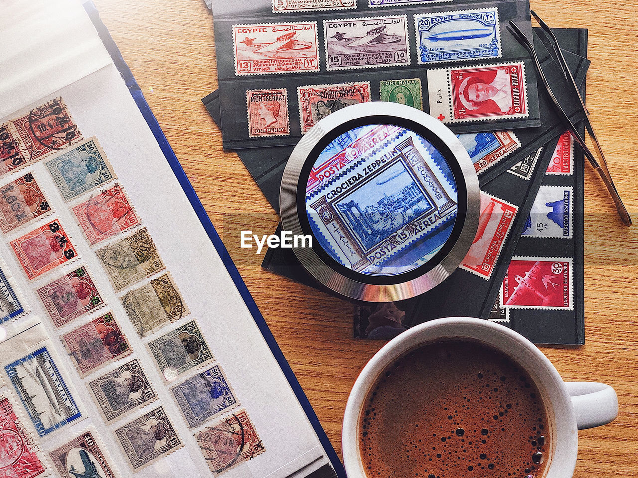 High angle view of a philatelic lay flat of old stamps with coffee on table
