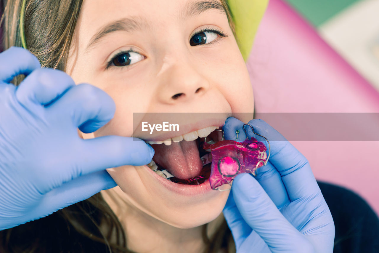 Cropped hands of dentist examining girl teeth