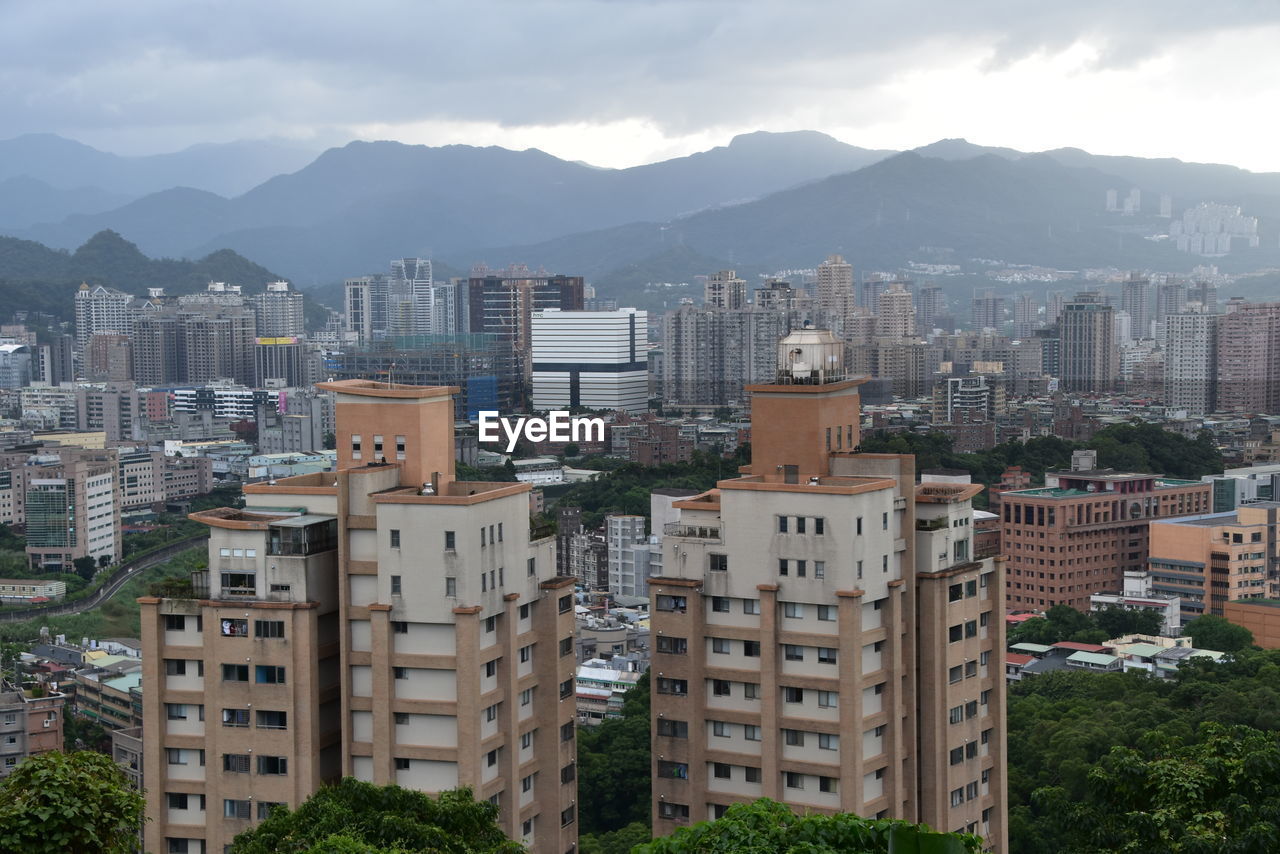 HIGH ANGLE VIEW OF BUILDINGS IN CITY AGAINST MOUNTAINS