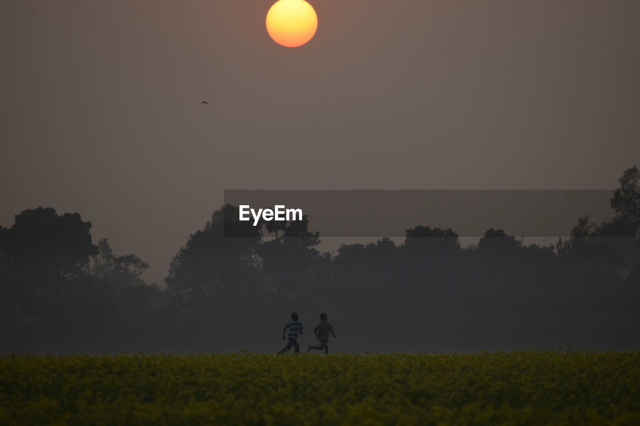 SILHOUETTE PEOPLE ON FIELD AGAINST CLEAR SKY DURING SUNSET