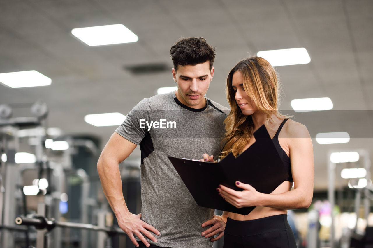 Trainer discussing with man in gym