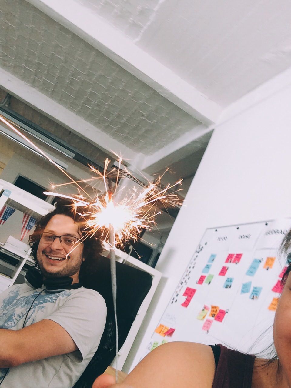 Young man looking at woman holding sparkler in office