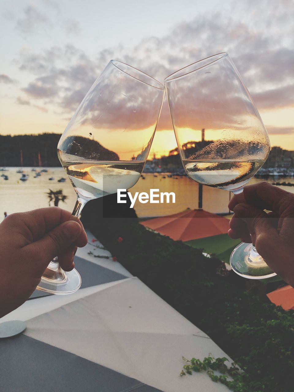 Close-up of hand holding wine glass against sky