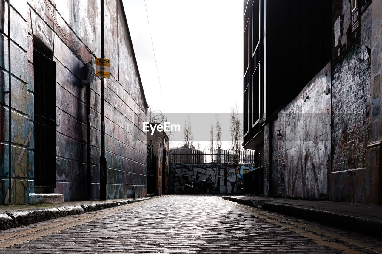 NARROW ALLEY AMIDST BUILDINGS AGAINST SKY