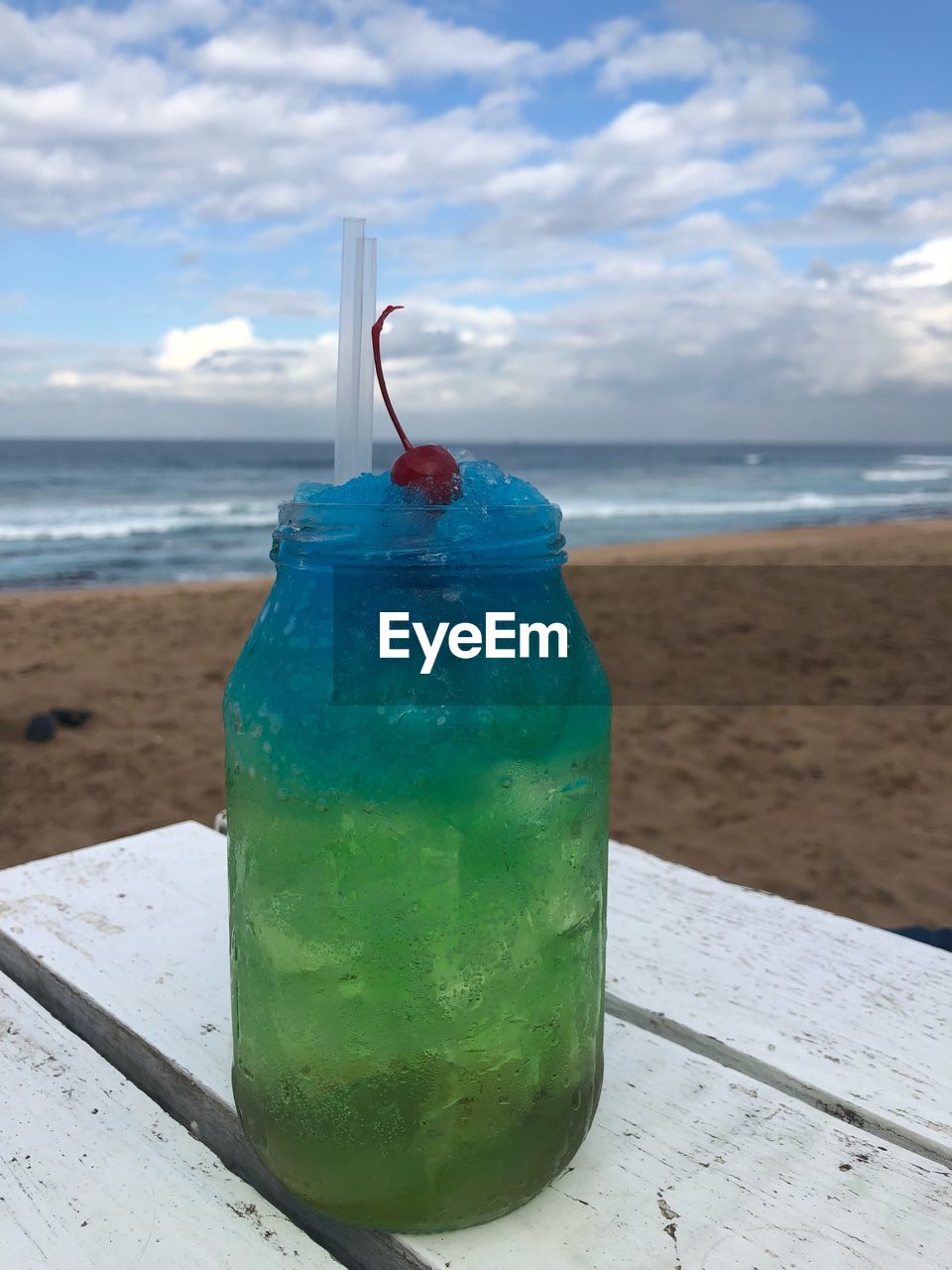 VIEW OF DRINK ON TABLE AT BEACH