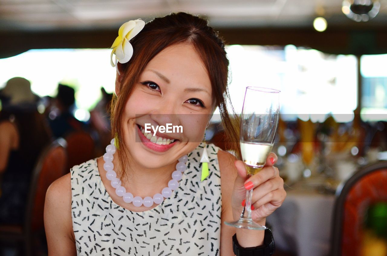 Portrait of smiling young woman holding champagne flute at restaurant