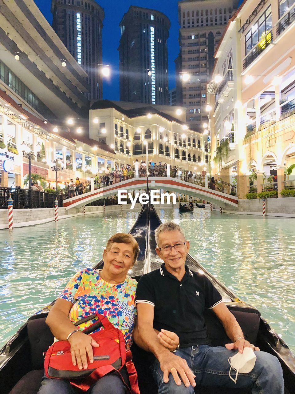 Old couple on a boat against bridge and city lights