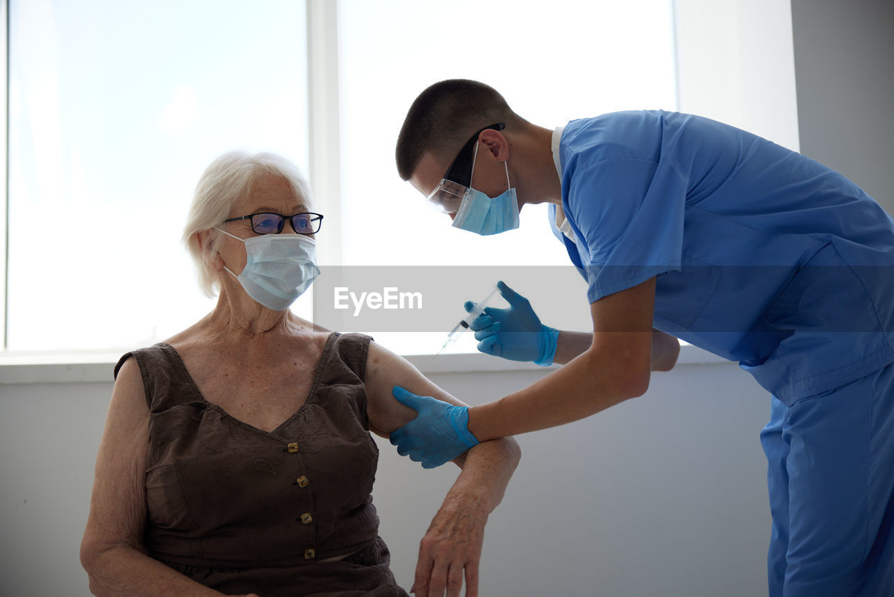 Doctor wearing mask vaccinating patient