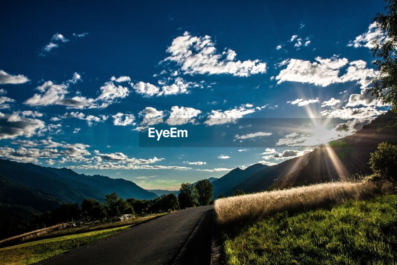 ROAD BY FIELD AGAINST SKY