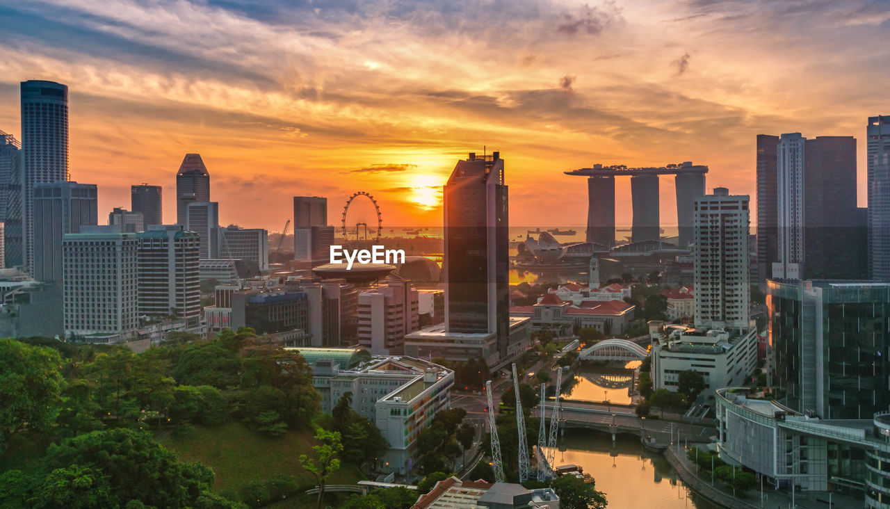 HIGH ANGLE VIEW OF BUILDINGS AGAINST SKY AT SUNSET