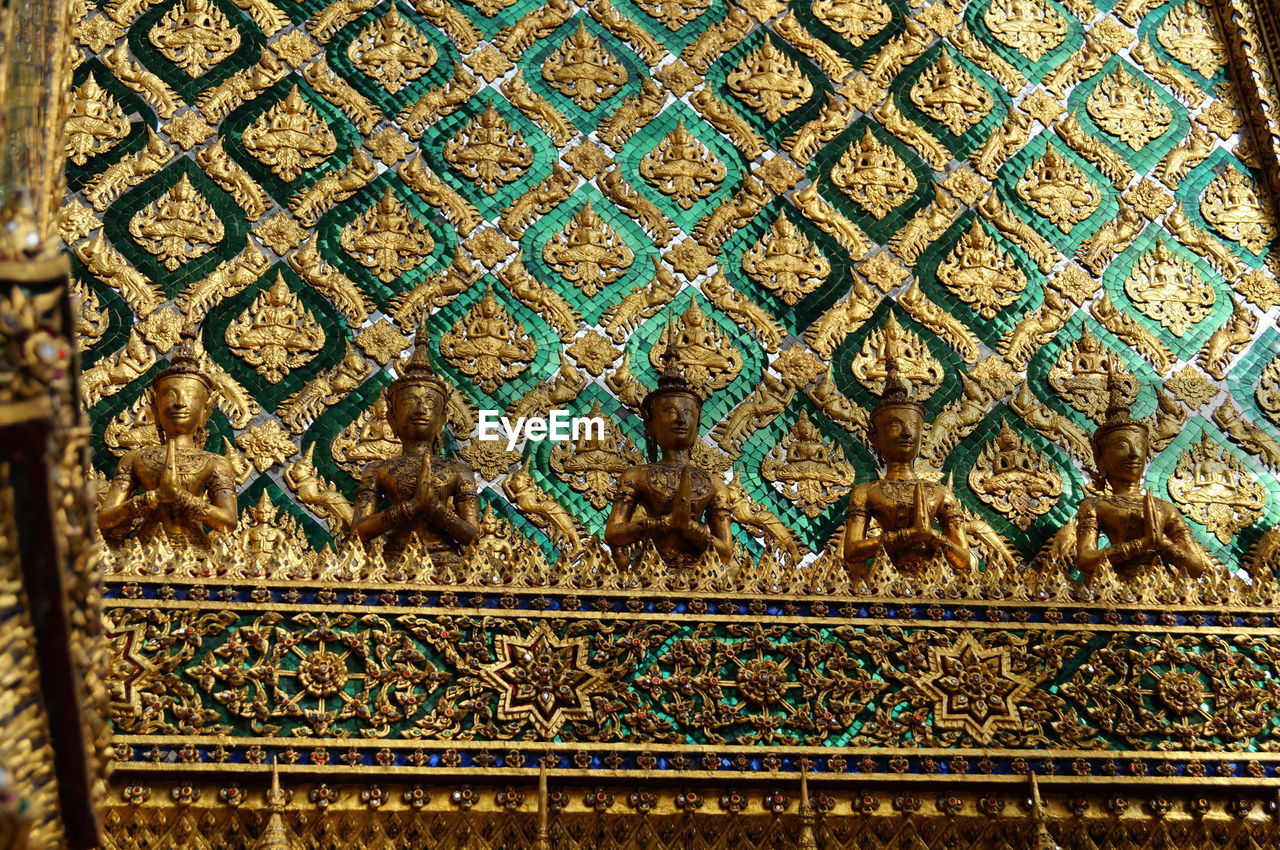 Low angle view of buddha figurines against ornate wall