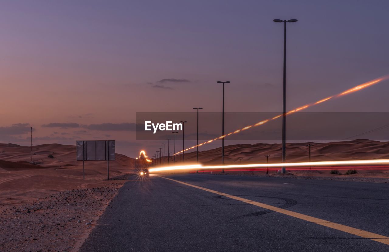 Illuminated road against sky at night