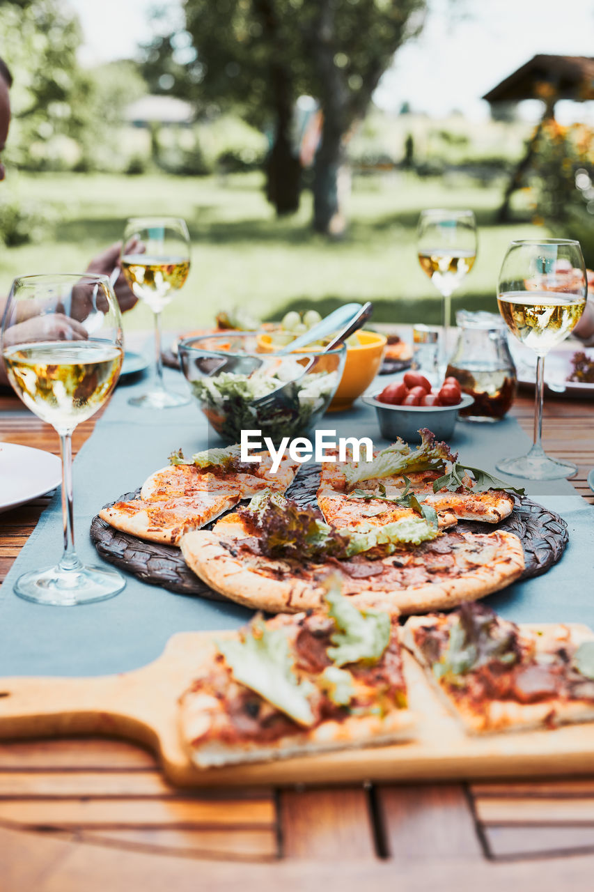 Dinner in a home garden. pizza, salads, fruits and white wine on table in a orchard in a backyard