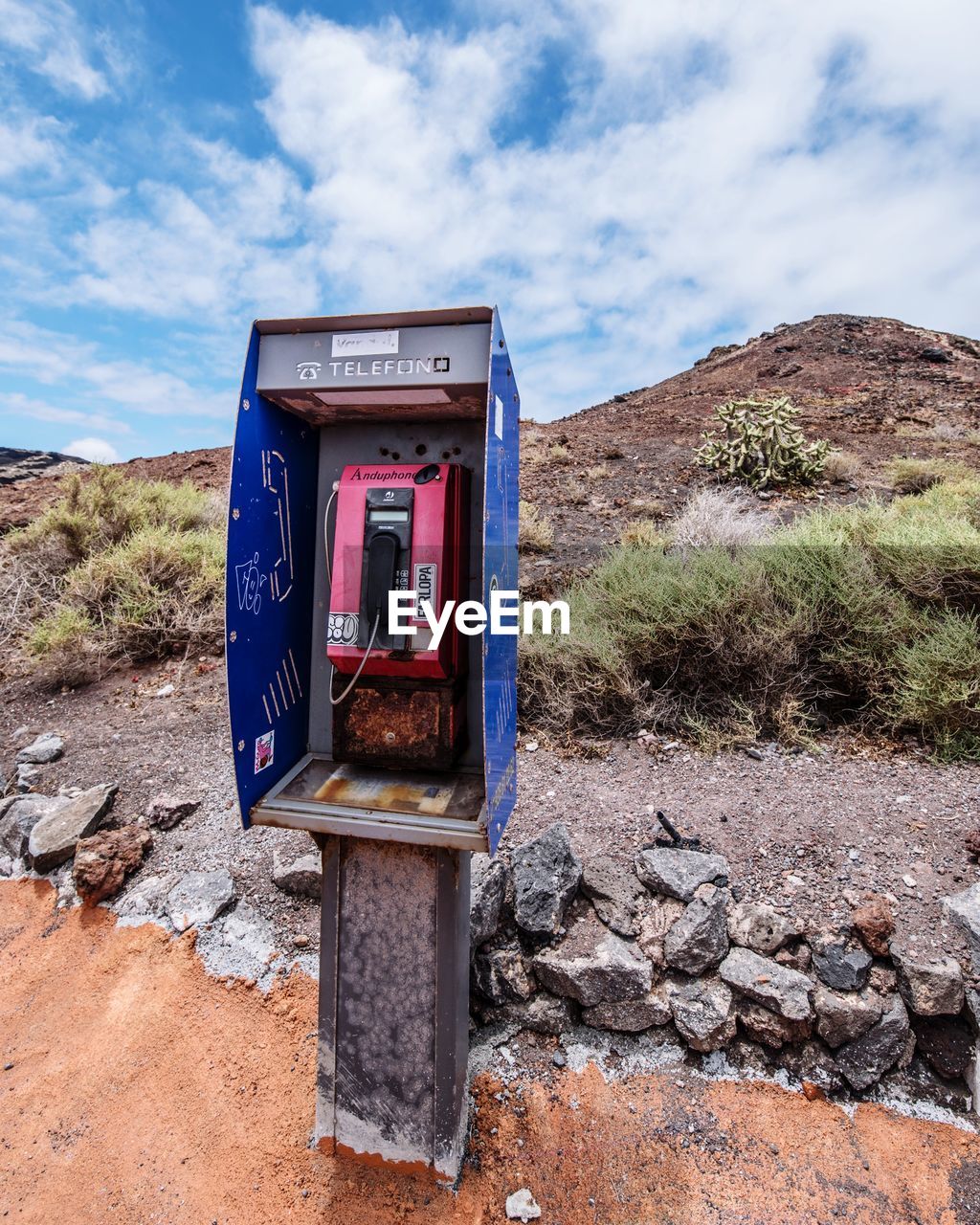 Telephone booth on field against cloudy sky