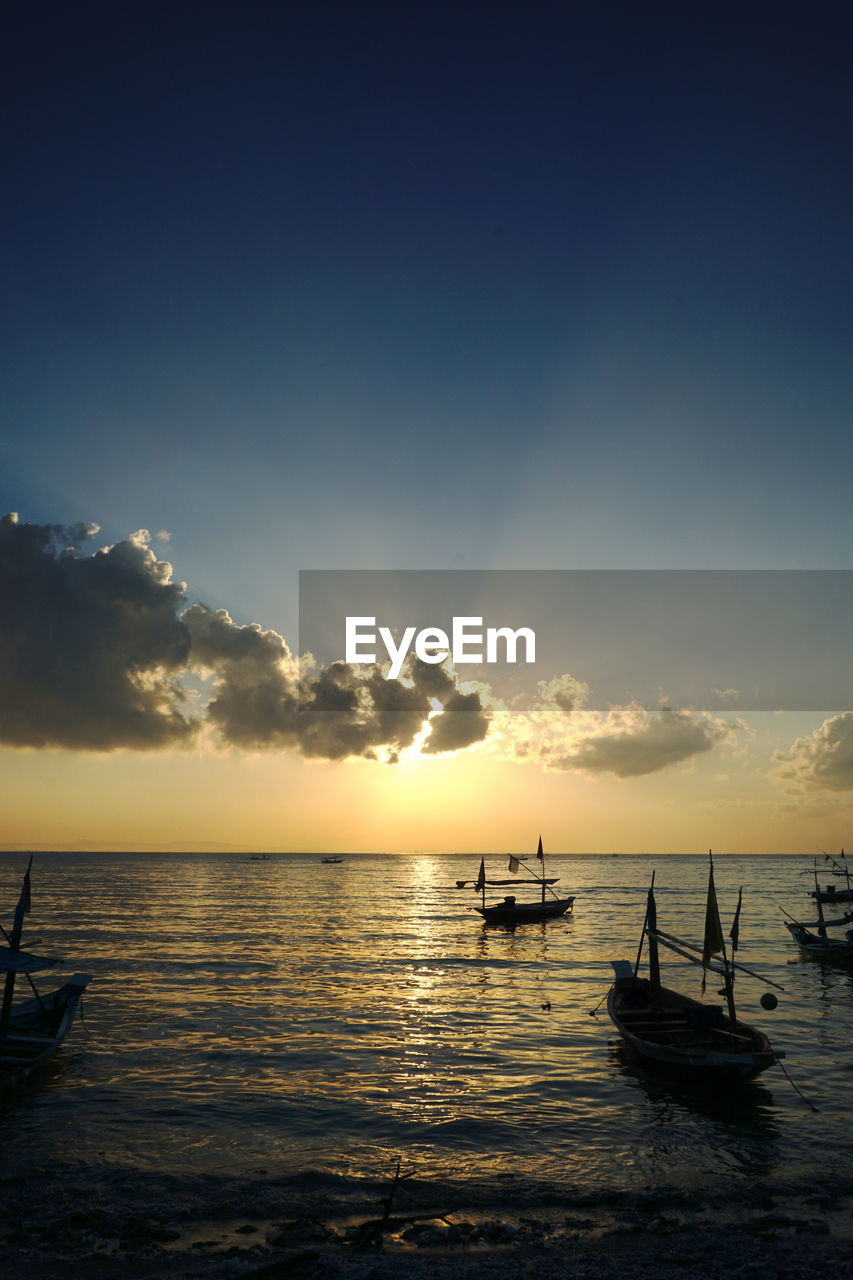 Silhouette boats in sea against sky during sunset