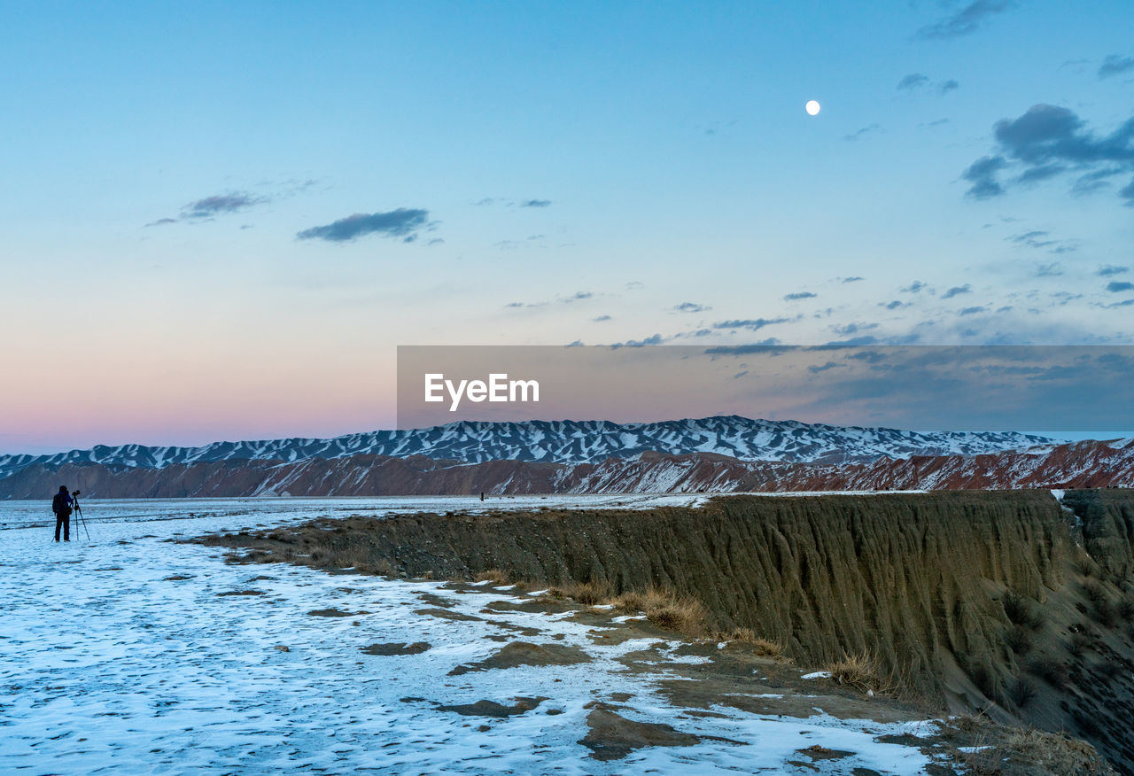 Scenic view of snow covered mountains against sky during sunset