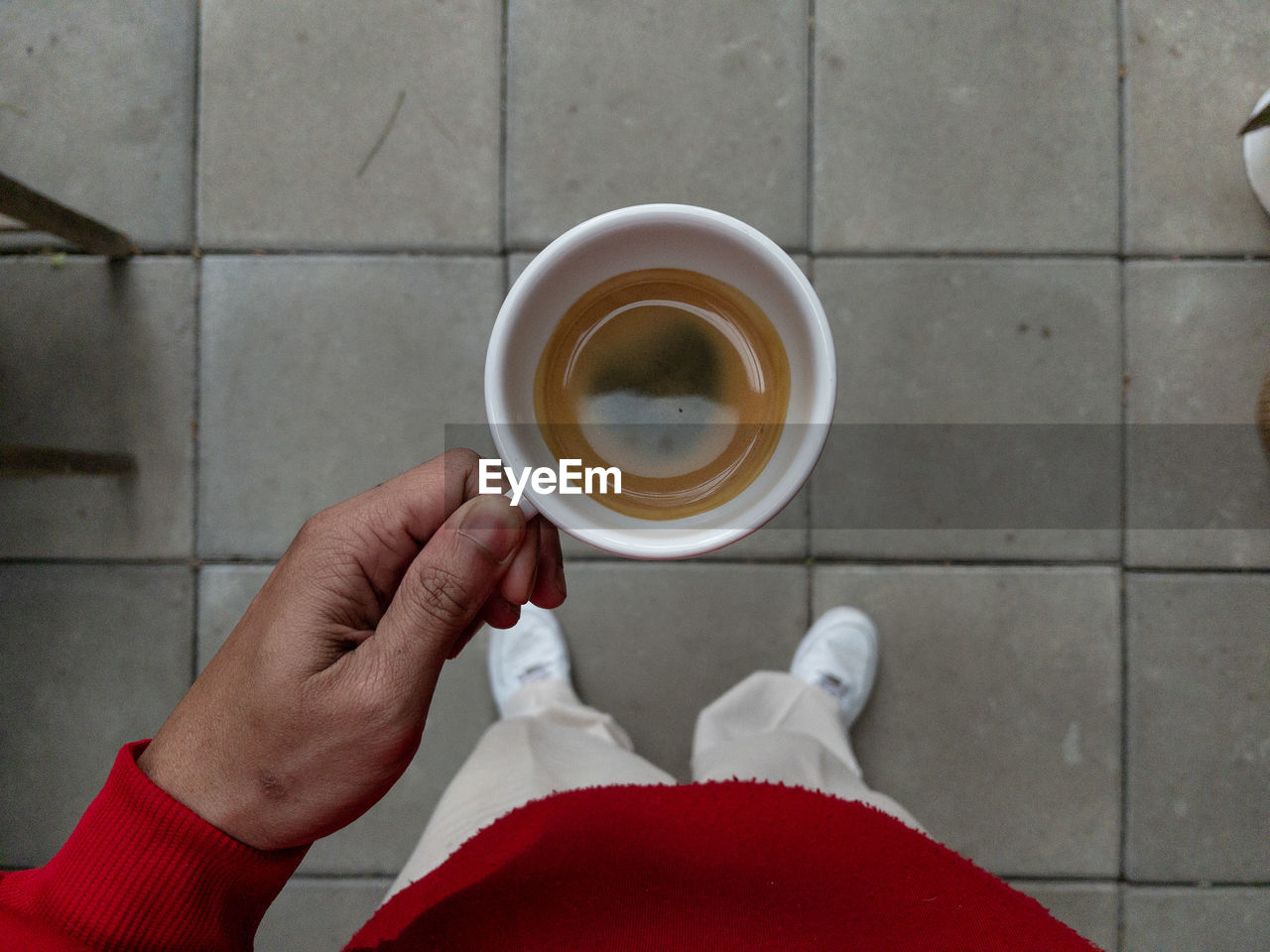 Midsection of person holding coffee cup on floor