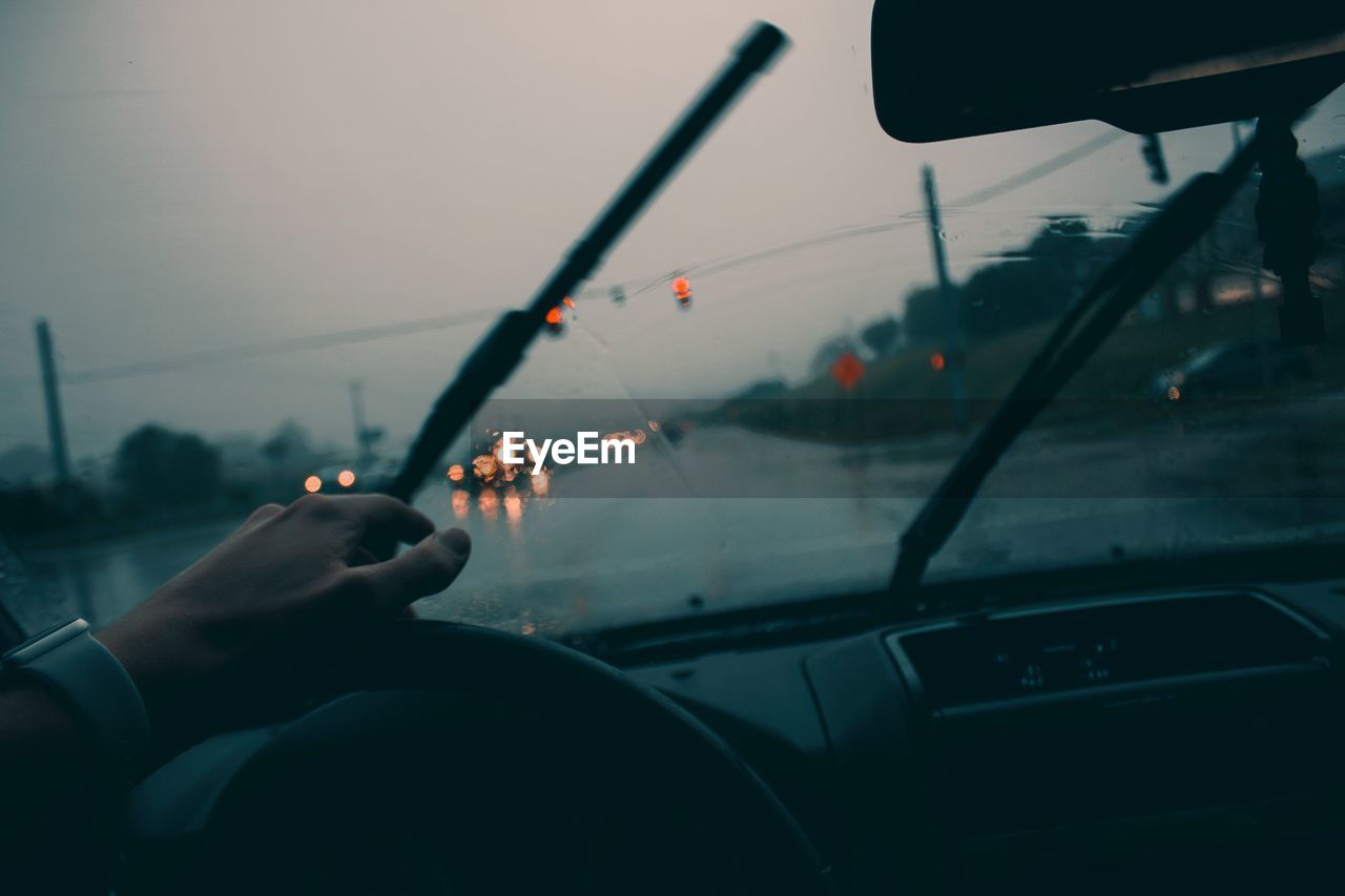 Cropped hand driving car during rainy season