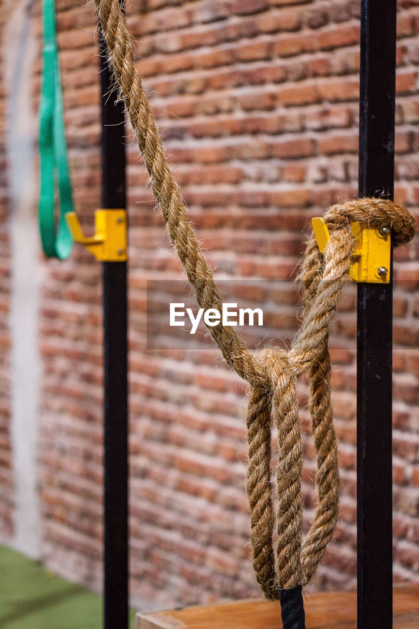 Rope hanging against brick wall