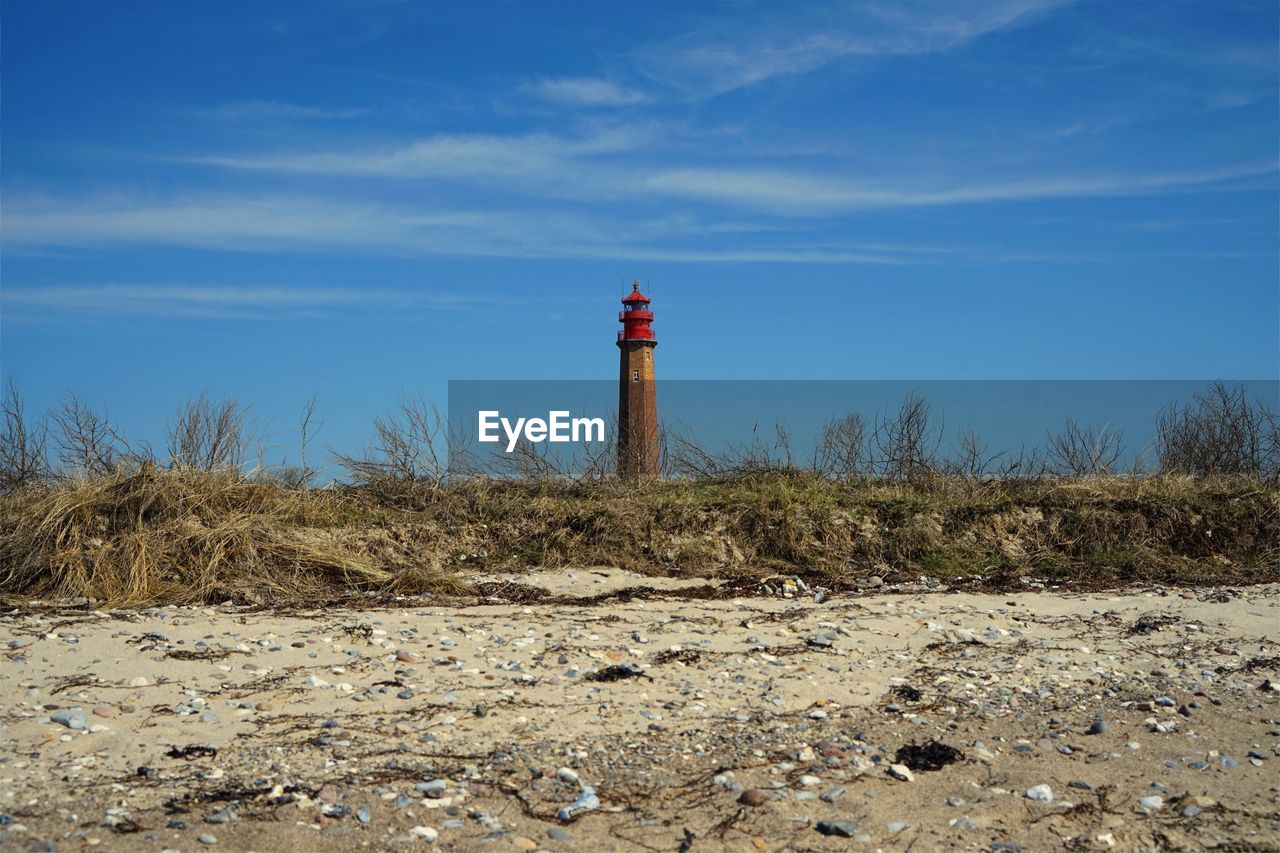 Lighthouse on field against sky