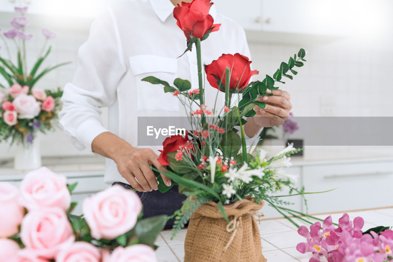 Midsection of woman holding rose bouquet on table