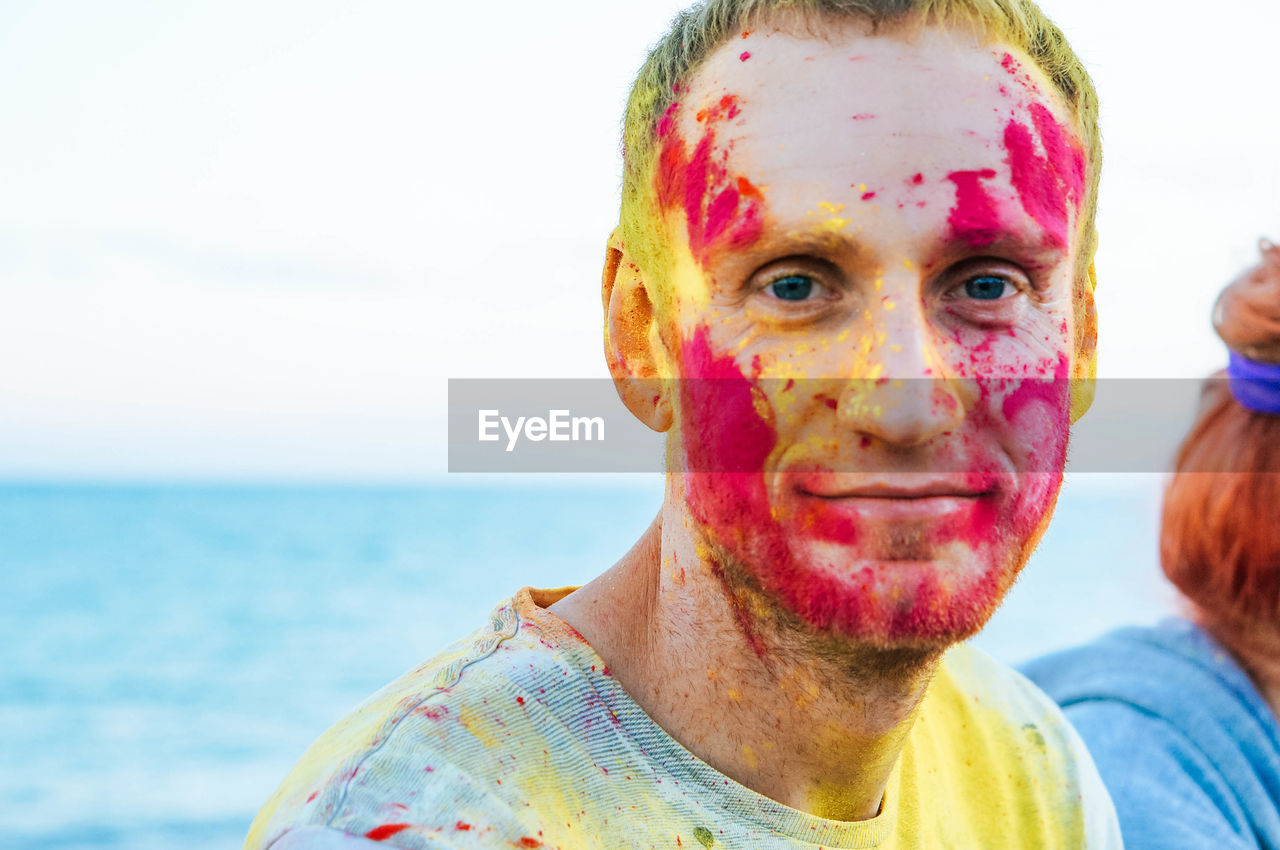 Close-up portrait of man with powder paint on face by sea