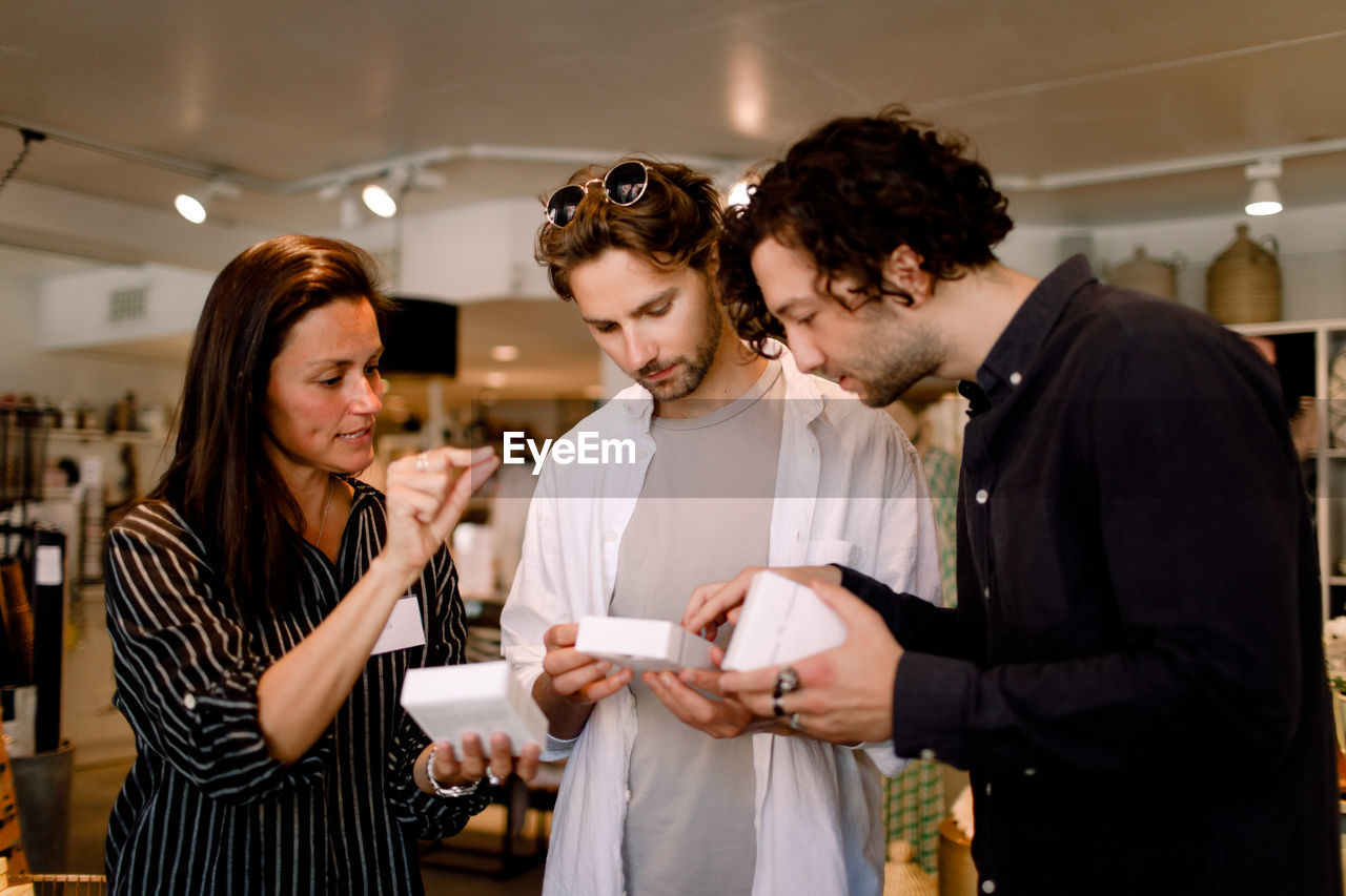 Saleswoman showing perfume box to male friends at store