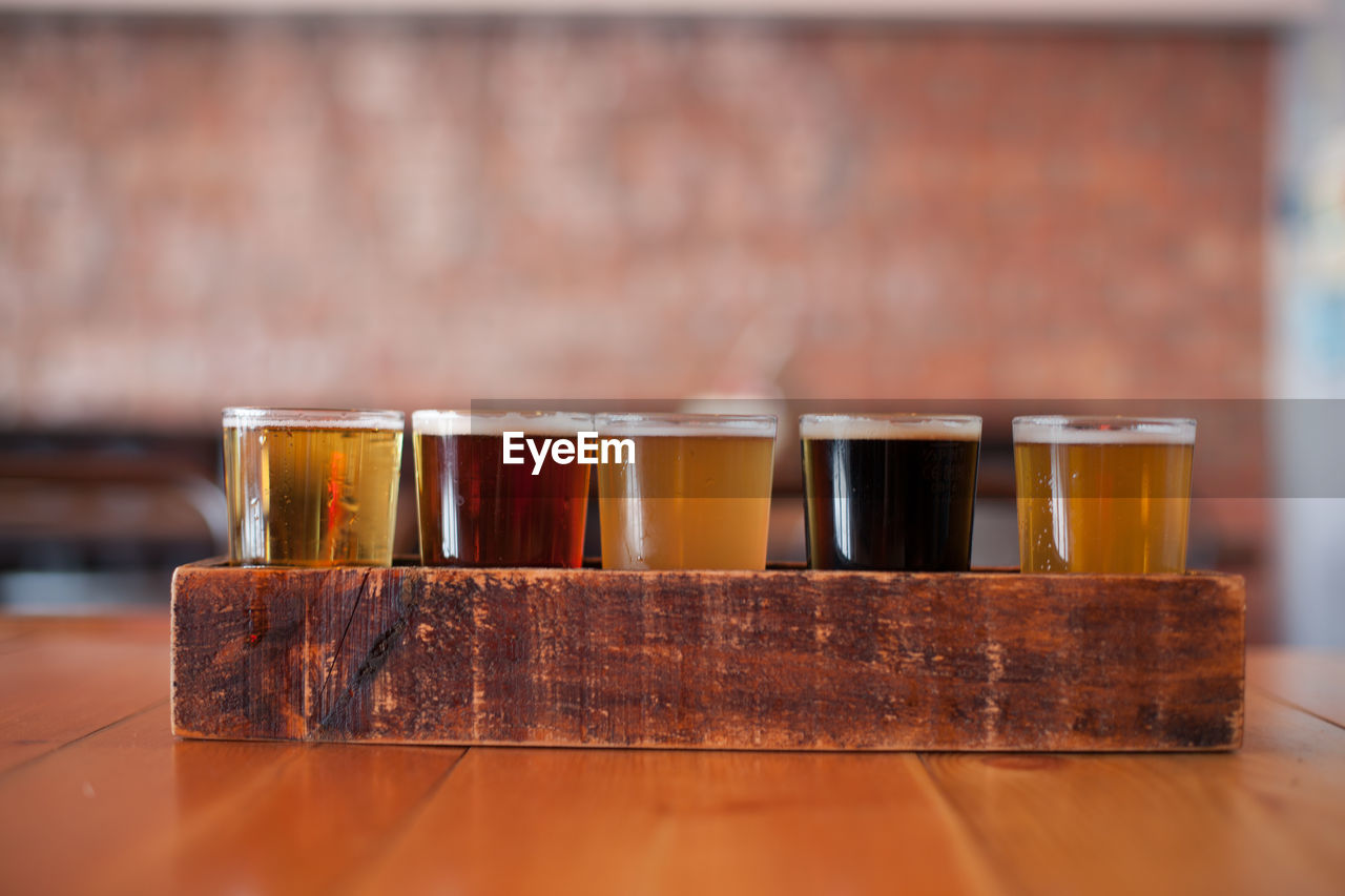 Close-up of various beer glass in wooden tray on table