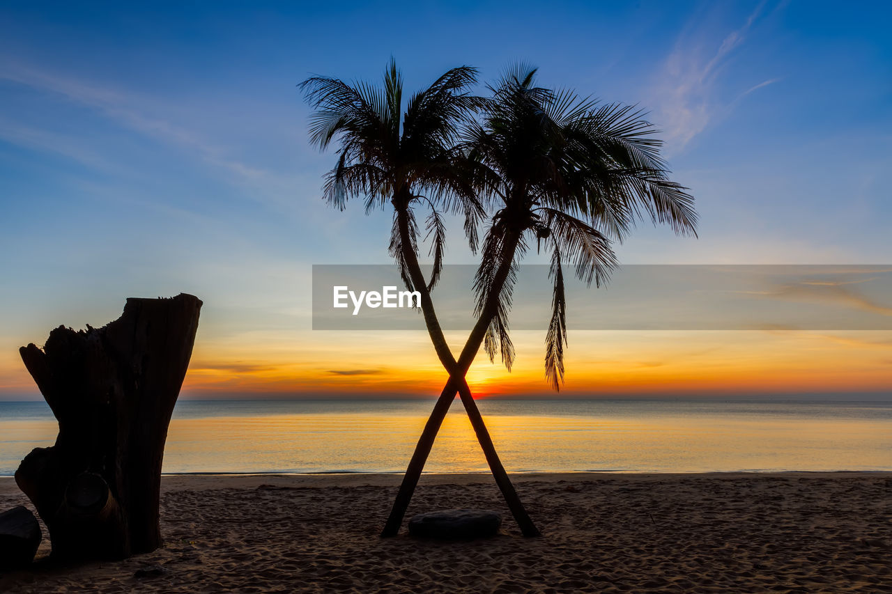 sky, sea, beach, water, land, sunset, palm tree, horizon, tropical climate, nature, ocean, beauty in nature, horizon over water, scenics - nature, tranquility, tranquil scene, tree, cloud, sunlight, sand, dusk, idyllic, shore, coast, silhouette, no people, travel destinations, plant, outdoors, coconut palm tree, evening, vacation, sun, holiday, trip, body of water, seascape