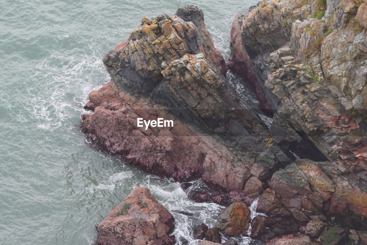 HIGH ANGLE VIEW OF ROCK FORMATIONS ON SEA SHORE
