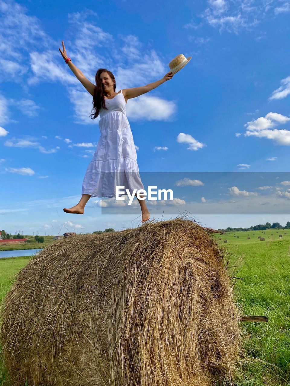 Rear view of woman jumping on field against sky