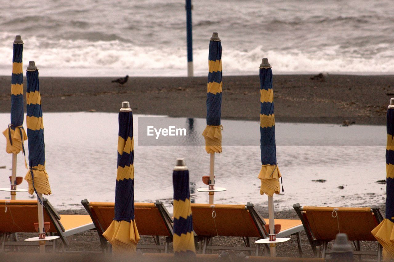 Closed parasols with deck chairs at beach